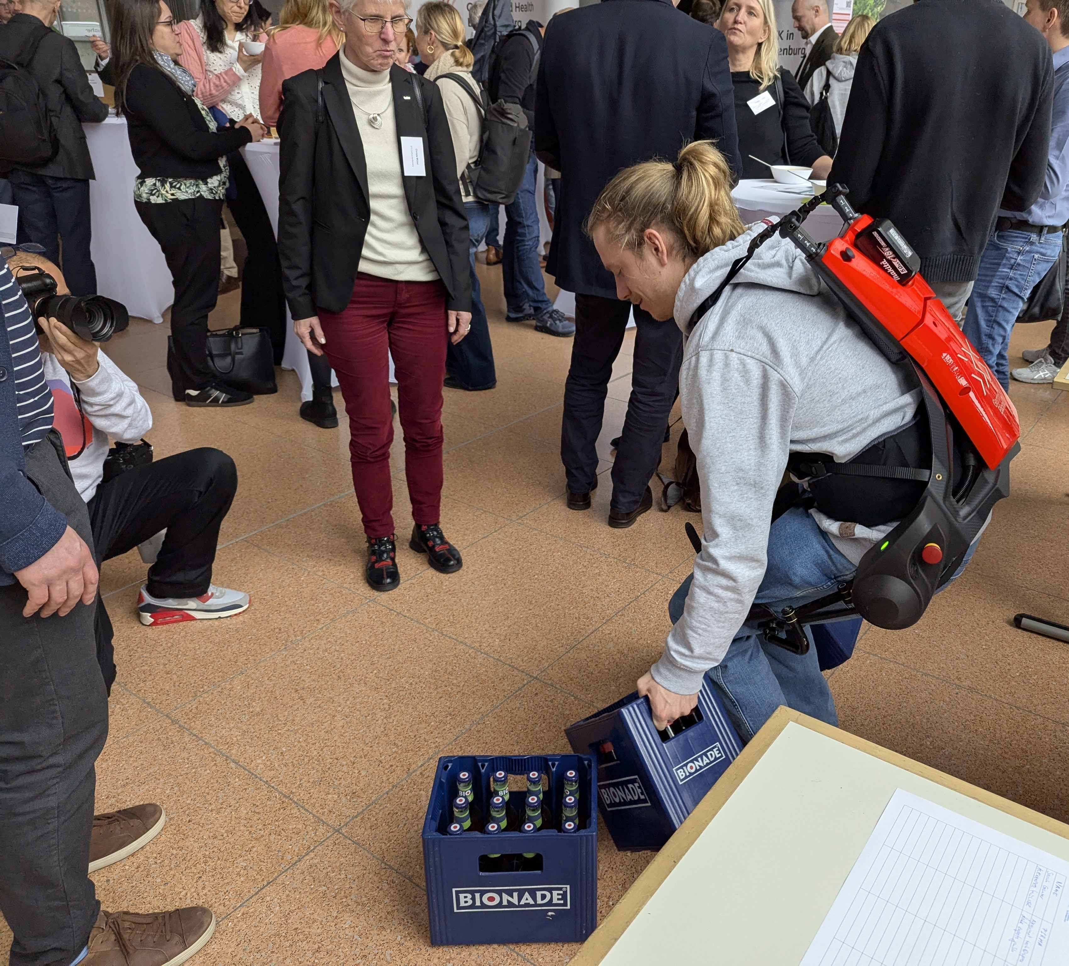 Exoskellett in Aktion beim Hochheben von Flaschenkisten mit Publikum