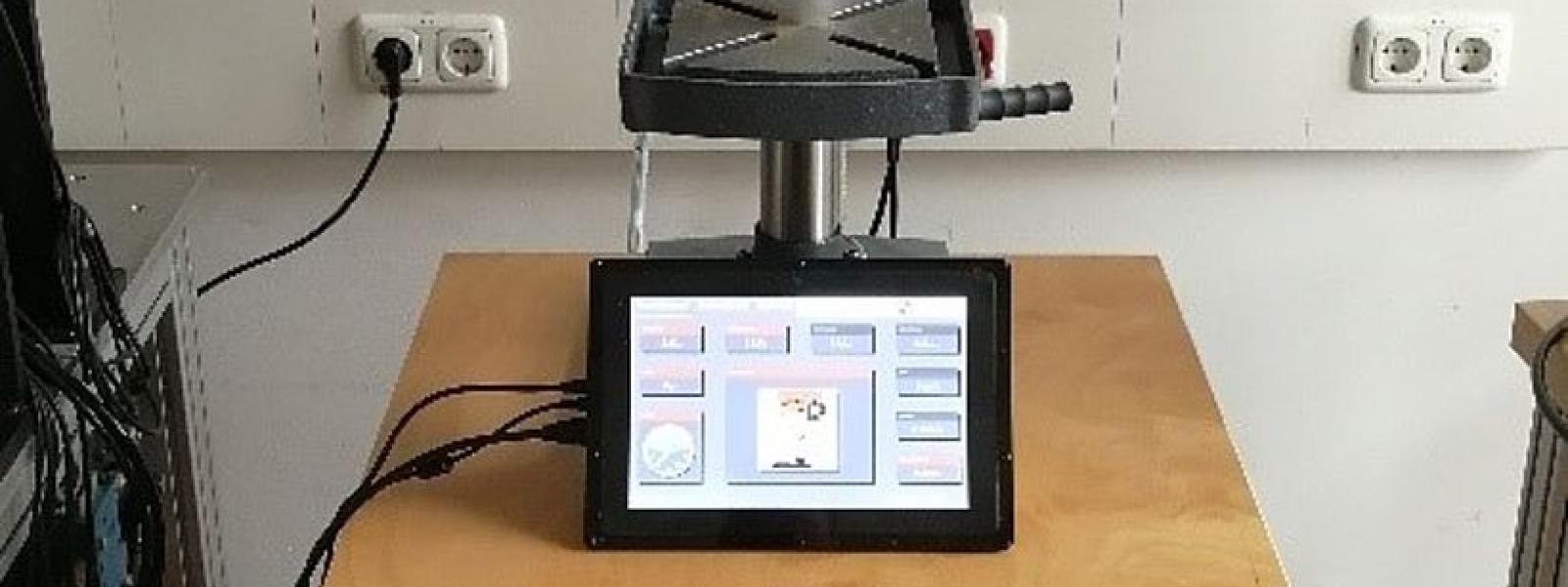Blick auf den Bohrtisch einer Ständerbohrmaschine; davor steht ein Tablet.