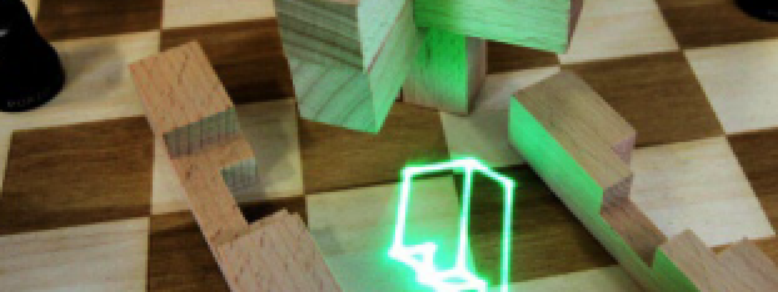 Ineinandergesteckte Holzformteile und ein überlagert dargestelltes laserprojiziertes grün leuchtendes Formteil